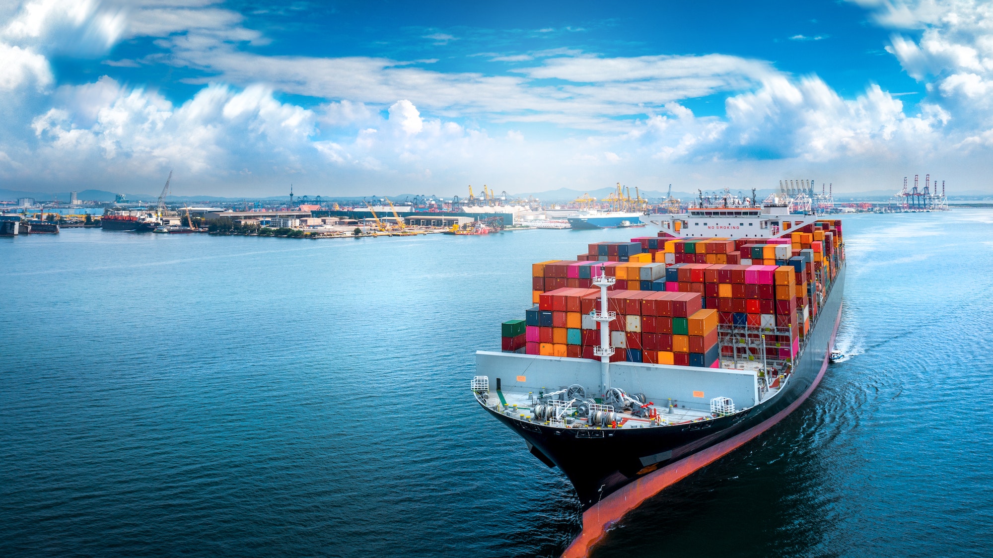 Aerial side view of cargo ship carrying container and running for export